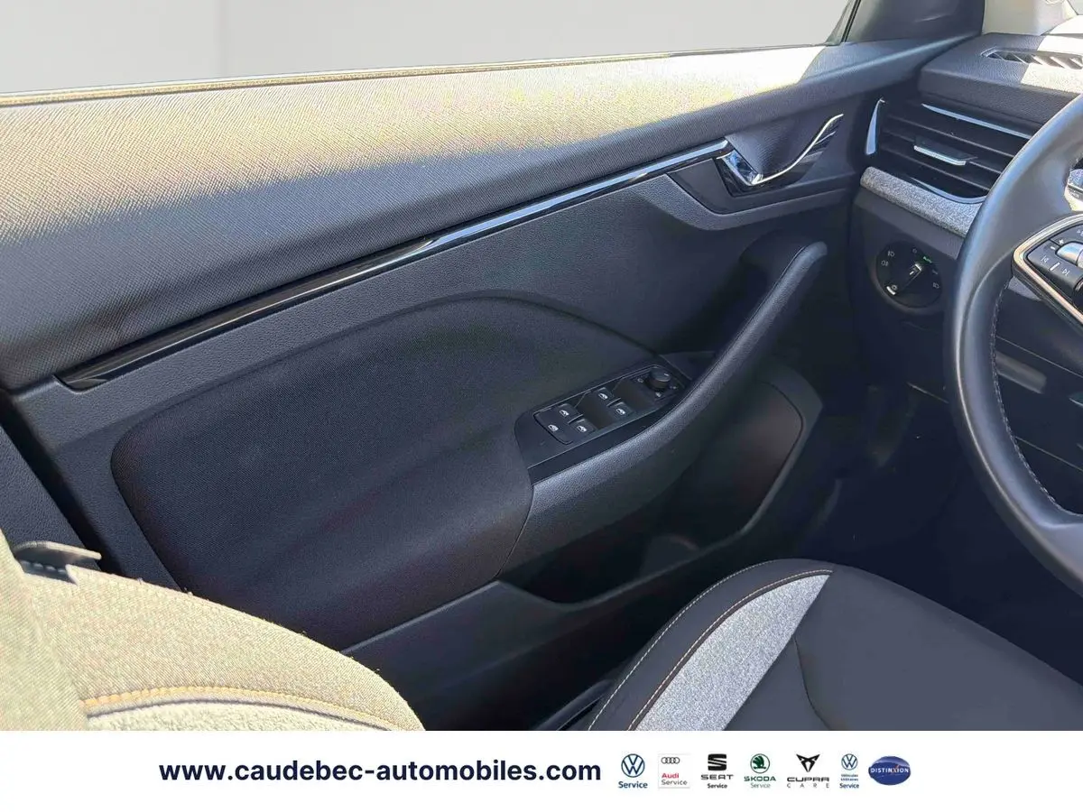 Intérieur côté conducteur du Skoda Kamiq 2025, montrant la portière noire avec commandes des vitres et partie du siège tissu gris et noir.