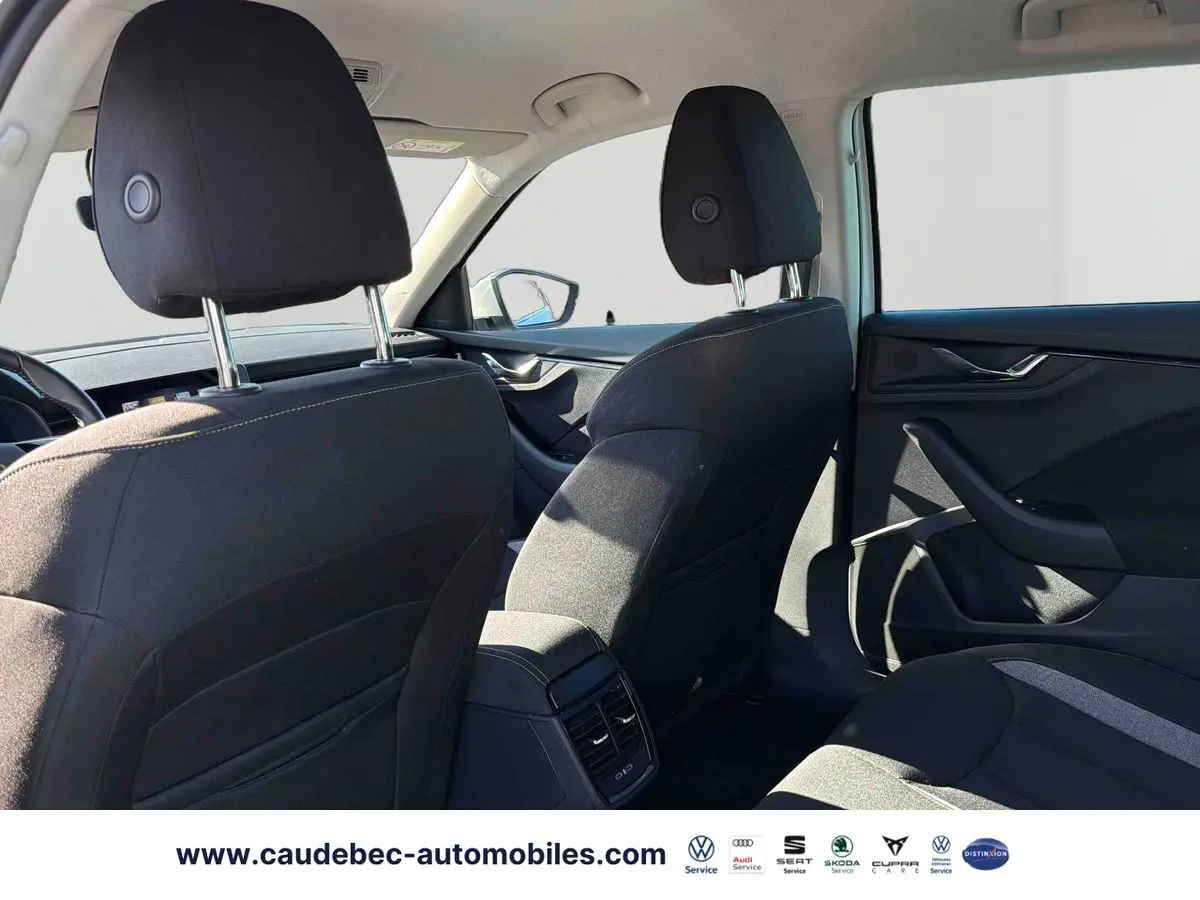 Vue intérieure arrière du Skoda Kamiq blanc, montrant les sièges noirs et les aérateurs centraux arrière.