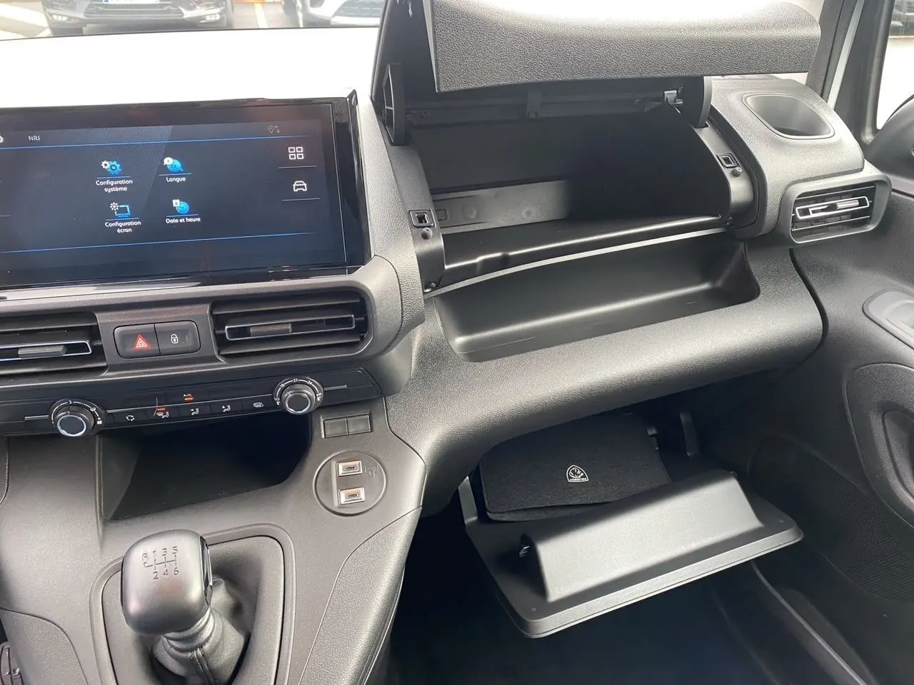 Vue intérieure du tableau de bord côté passager du Peugeot Partner 2024 blanc, avec boîte manuelle et double boîte à gants ouverte.