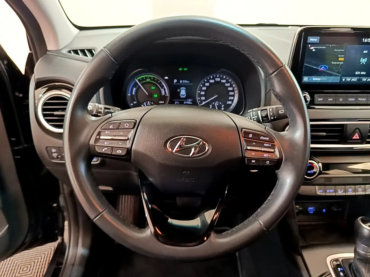 Vue centrée sur le volant cuir noir d'une Hyundai Kona 2020, avec tableau de bord et écran tactile de navigation visibles.