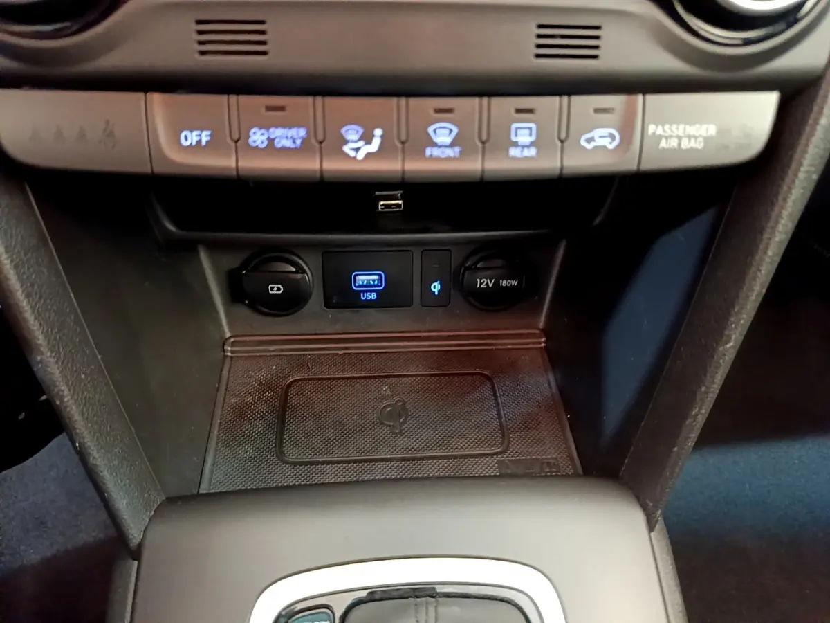 Détail de la console centrale du Hyundai Kona noir 2020 montrant ports USB, prise 12V et zone de recharge sans fil Qi.
