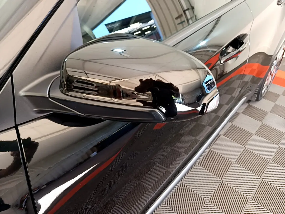 Gros plan sur le rétroviseur côté gauche noir brillant du Hyundai Kona 1.6 GDi Hybrid 2020, avec reflet de l'environnement intérieur.