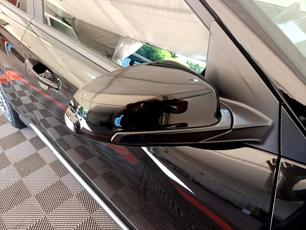 Rétroviseur noir côté gauche du Hyundai Kona 2020 hybride, avec porte et poignée visibles en reflet.