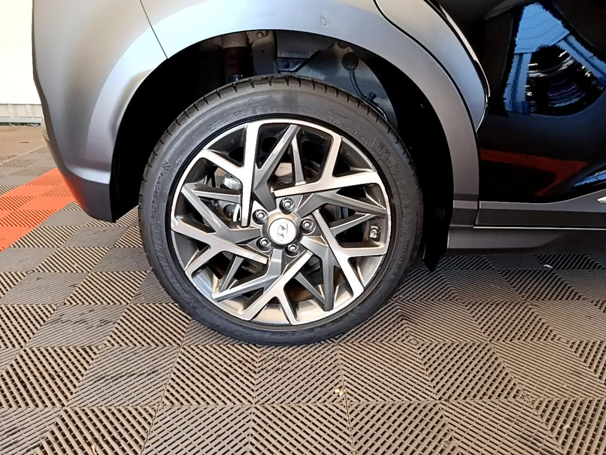 Gros plan sur la roue avant gauche du Hyundai Kona noir 2020, mettant en valeur la jante alliage au design géométrique.