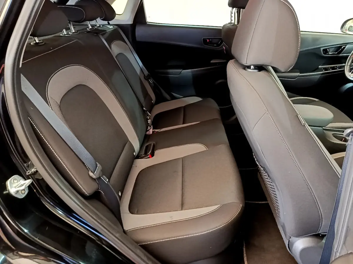 Vue intérieure côté gauche montrant la banquette arrière et le siège avant du Hyundai Kona noir 2020 hybride.