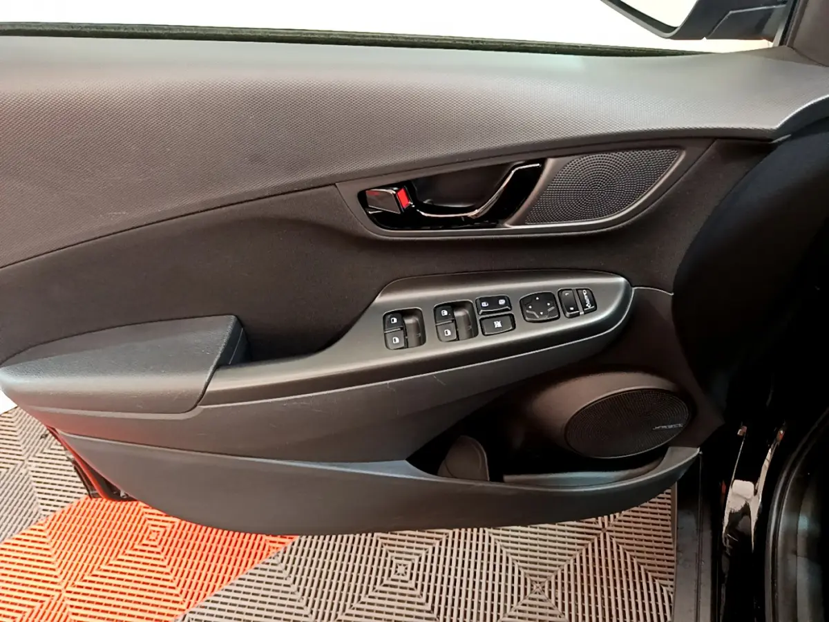 Vue rapprochée de la porte avant gauche noire du Hyundai Kona 1.6 GDi Hybrid avec commandes électriques et haut-parleur Bose.