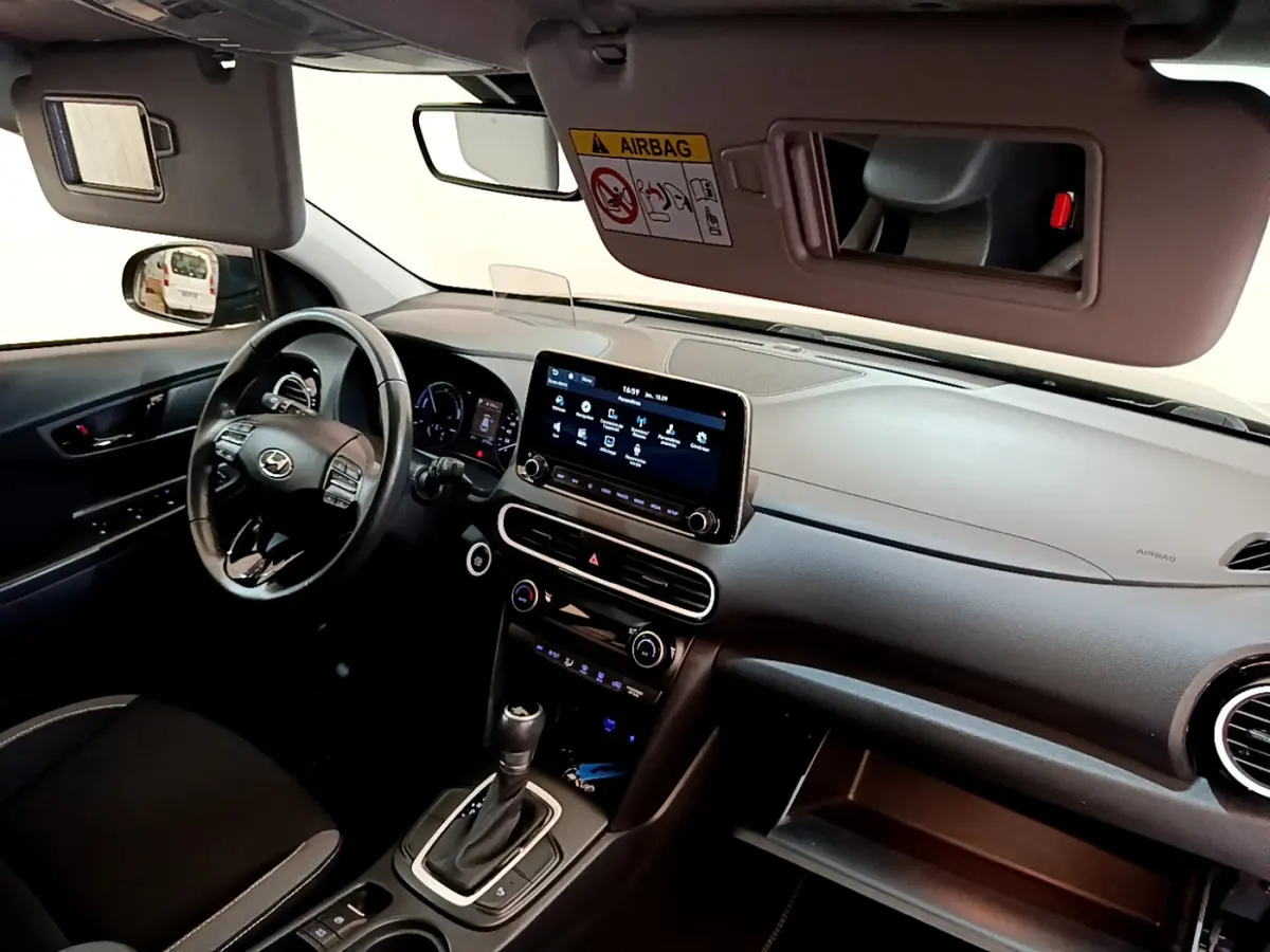 Vue intérieure côté conducteur du tableau de bord noir du Hyundai Kona 1.6 GDi Hybrid avec écran tactile central et volant multifonctions.