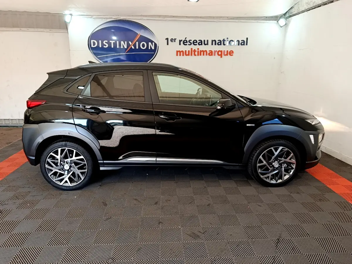 Profil côté gauche d'un Hyundai Kona noir 2020 hybride, avec jantes alliage et protections d'ailes grises.
