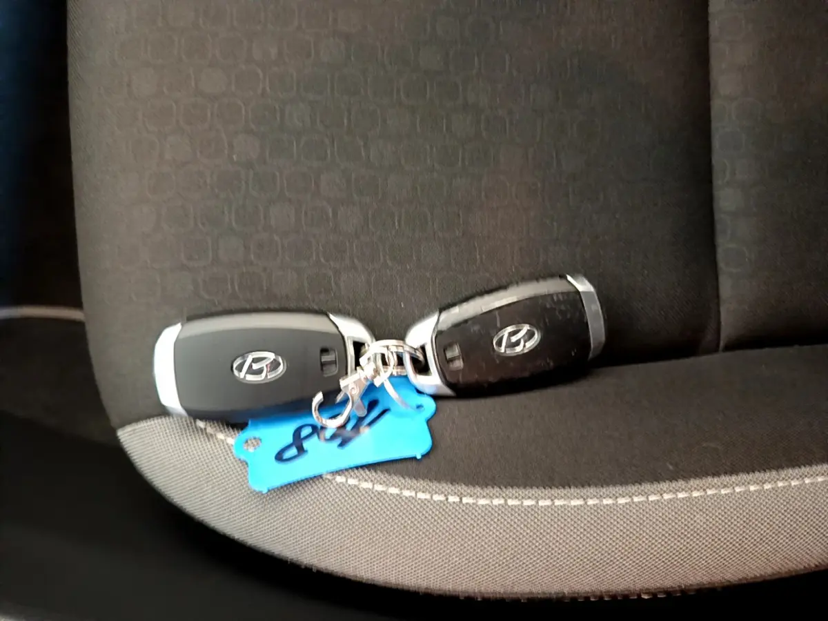 Deux clés Hyundai noires posées sur un siège tissu gris foncé à coutures apparentes, intérieur du Kona 2020.