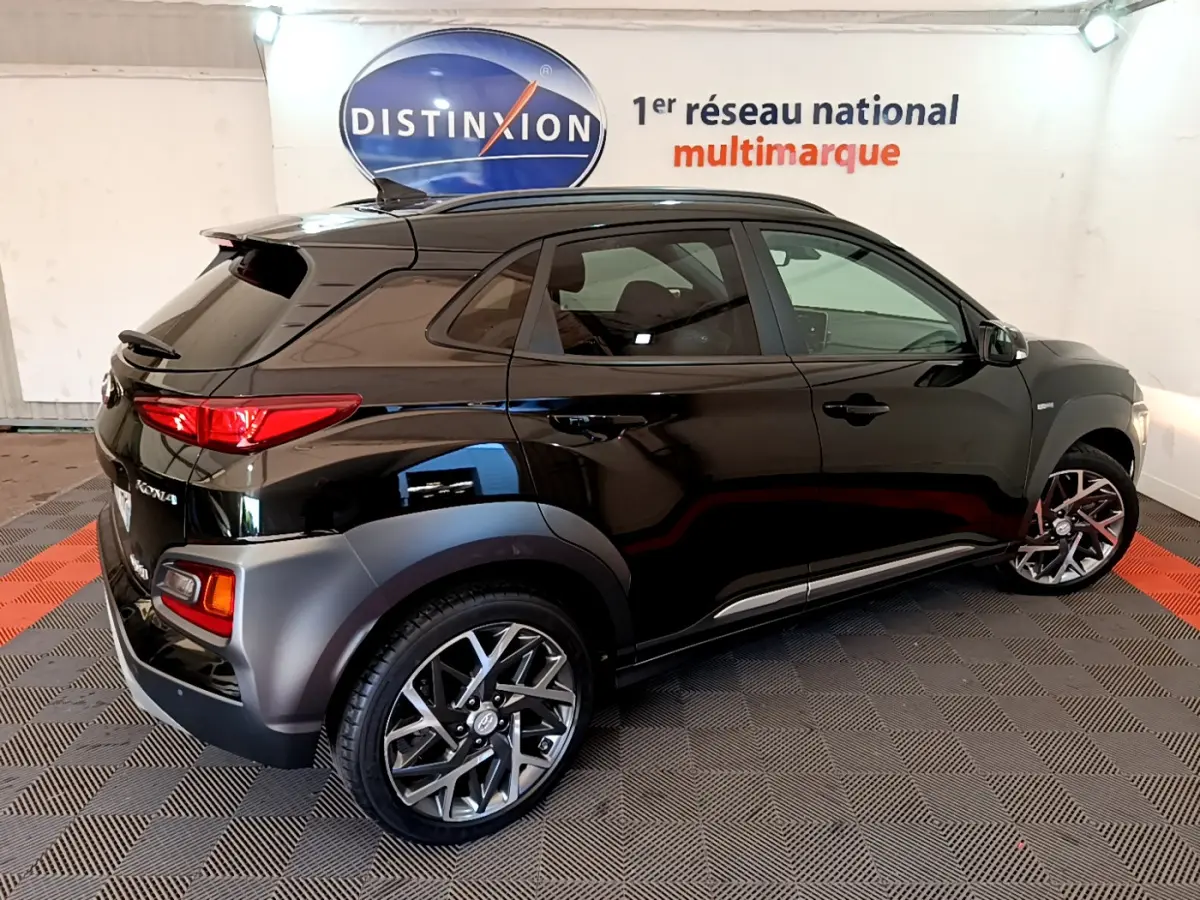 Vue 3/4 arrière droite d'un Hyundai Kona noir 2020 avec jantes alliage et protections grises sur les passages de roues.