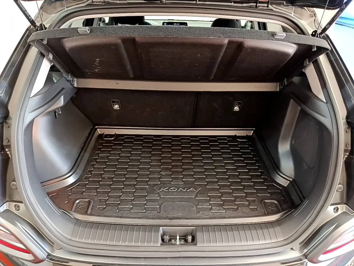 Coffre ouvert d'un Hyundai Kona noir 2020, montrant le tapis de coffre spécifique avec logo KONA.