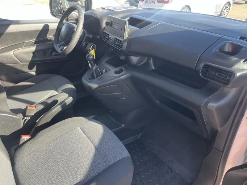 Intérieur du Citroën Berlingo Fourgon blanc, vue côté conducteur montrant tableau de bord et sièges tissu gris.