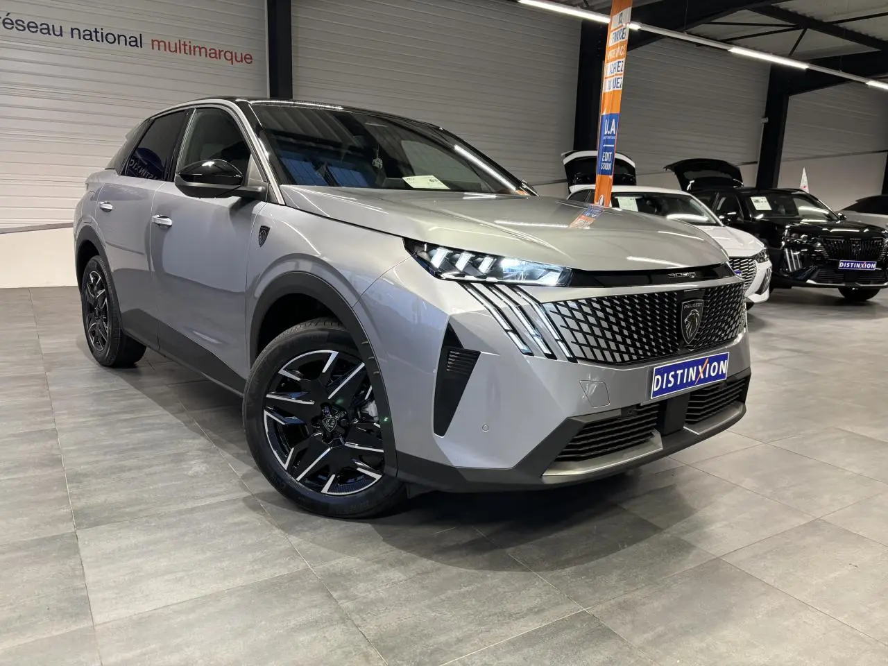 Peugeot 3008 Hybrid gris Artense en 3/4 avant droit, calandre noire à motif géométrique et jantes alliage noires.