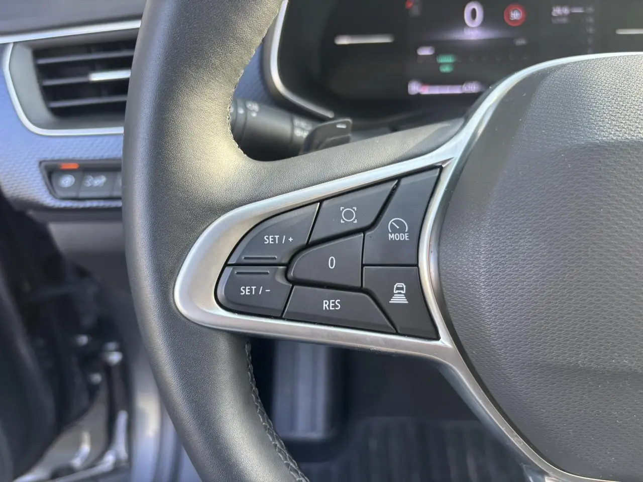 Gros plan sur les commandes à gauche du volant noir du Renault Arkana 2025 avec tableau de bord numérique en arrière-plan.