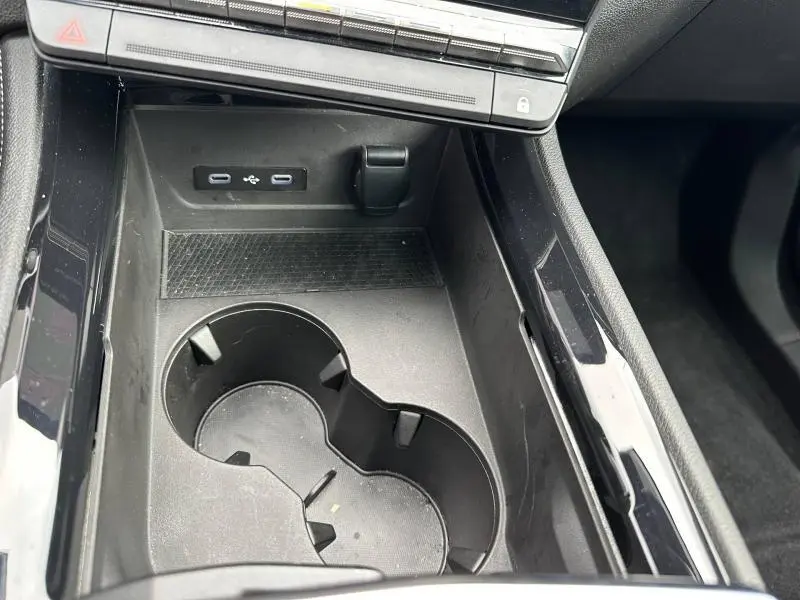 Gros plan sur la console centrale noire du Renault Austral 2025 avec porte-gobelets et ports USB-C visibles.