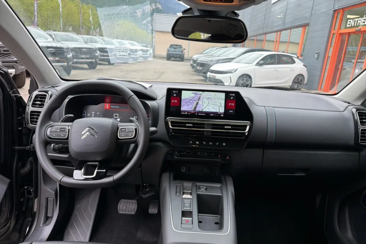 Vue intérieure avant du Citroën C5 Aircross noir 2025, tableau de bord moderne avec écran tactile et volant multifonctions.