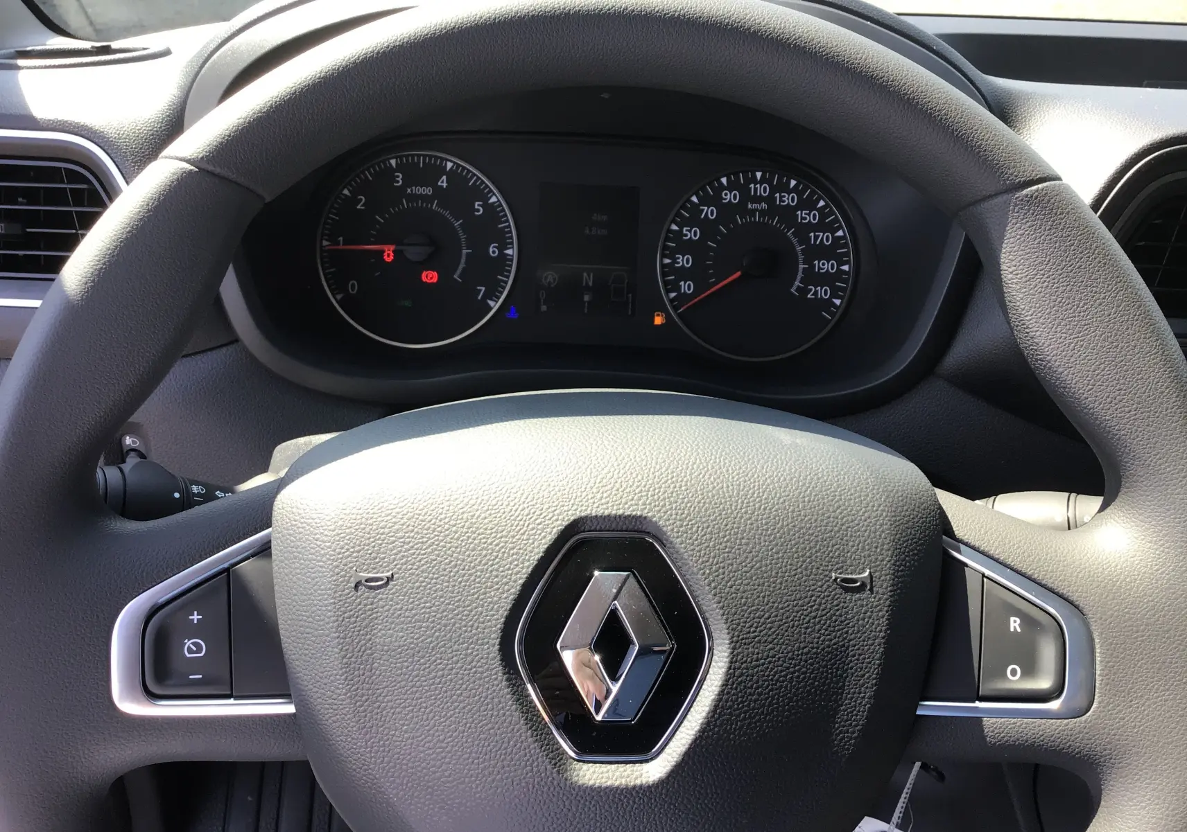 Vue rapprochée du volant gris avec logo Renault et tableau de bord du Master L2H2 2024 en arrière-plan.