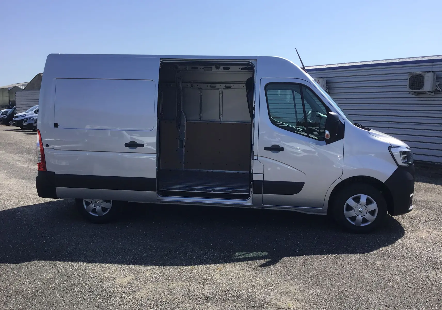 Vue latérale droite d'un Renault Master gris étoile 2024 avec porte coulissante ouverte montrant l'espace de chargement.