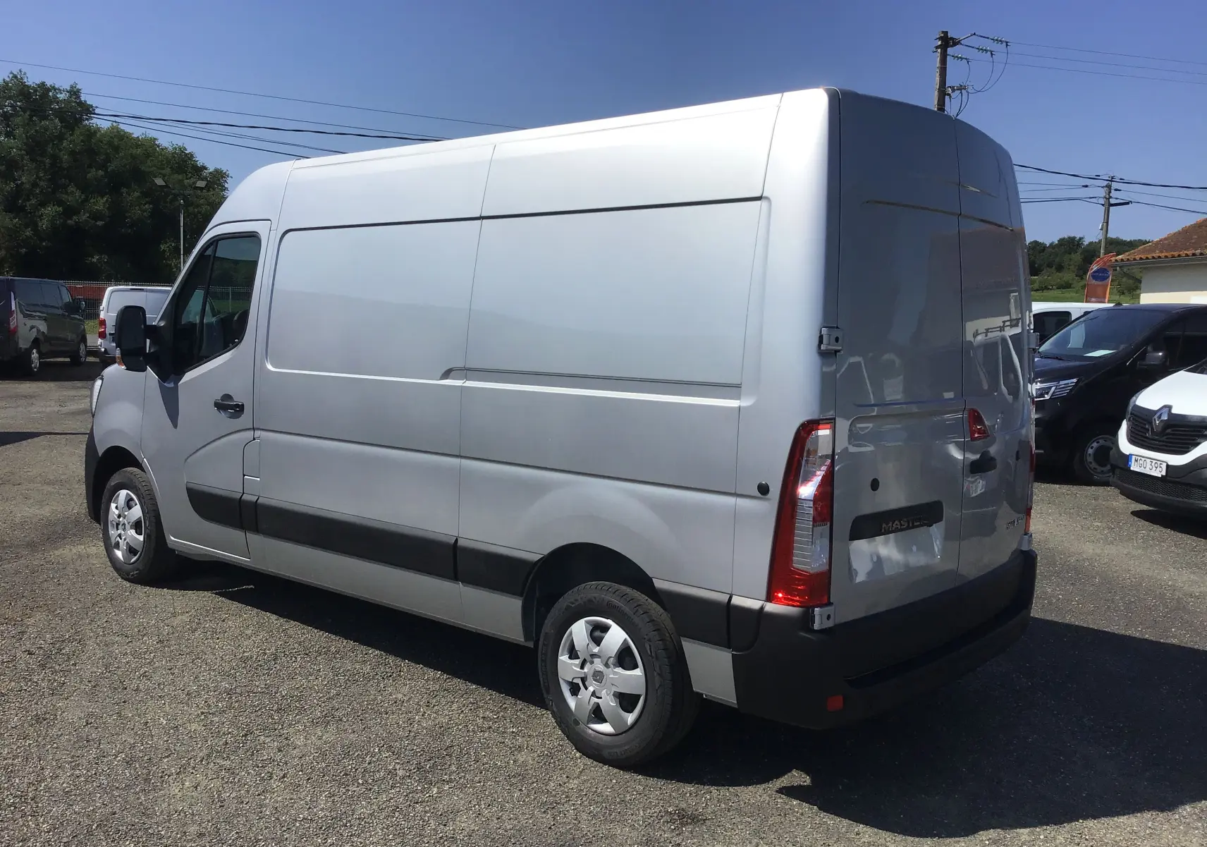 Renault Master gris étoile vu en 3/4 arrière droit, fourgon utilitaire avec enjoliveurs maxi et feux arrière verticaux.