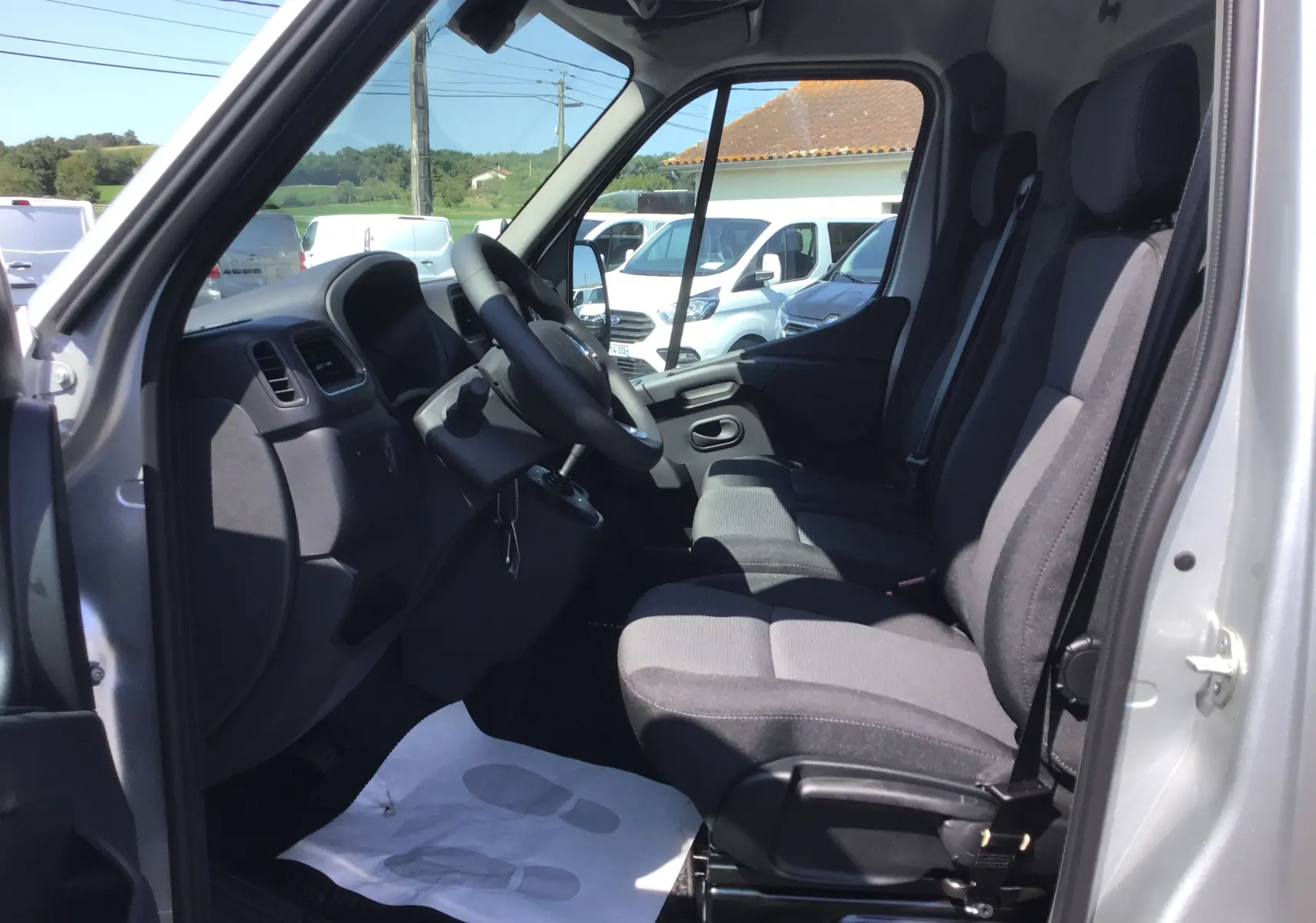 Intérieur côté conducteur du Renault Master gris étoile 2024, montrant les sièges et le tableau de bord depuis la porte ouverte.