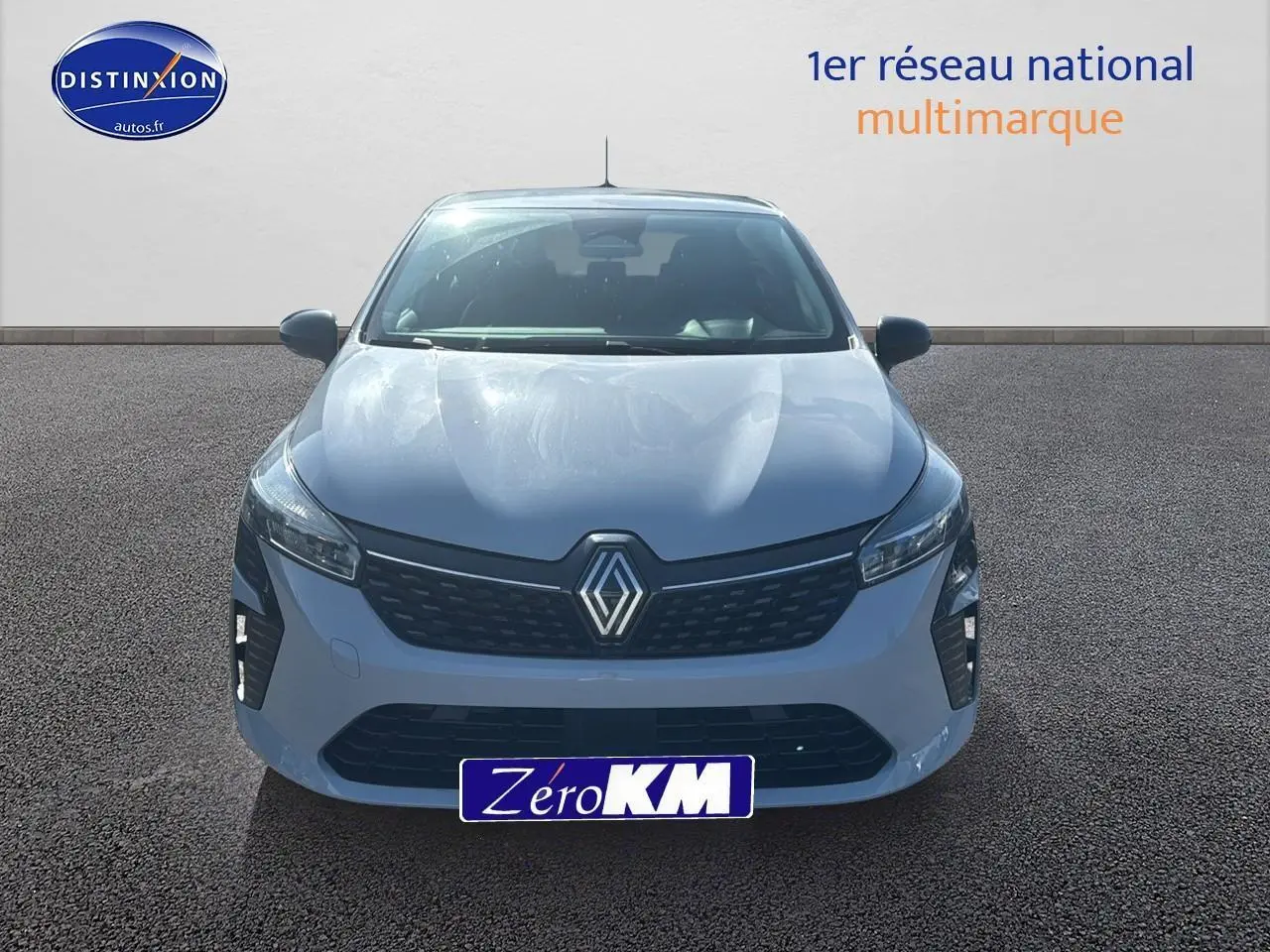 Renault Clio 2025 gris Rafale vue de face, avec calandre noire et projecteurs LED allumés.