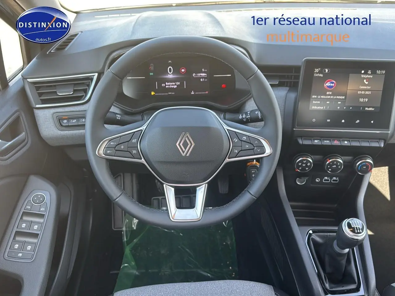 Intérieur de la Renault Clio 2025, vue de face sur le volant, tableau de bord numérique et levier de vitesses manuel.