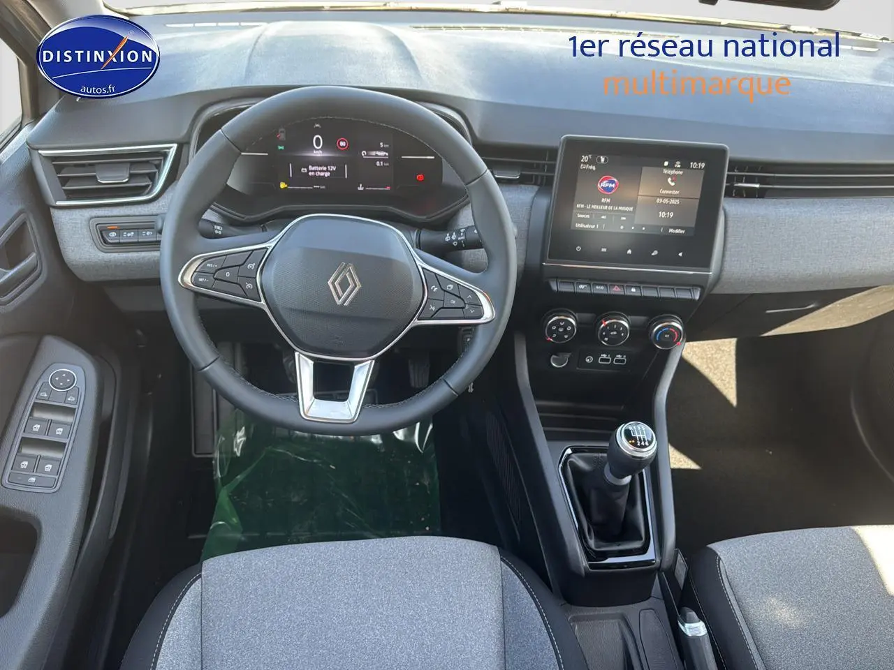 Vue intérieure de la Renault Clio 2025 montrant le volant, tableau de bord numérique et levier de vitesse manuel.