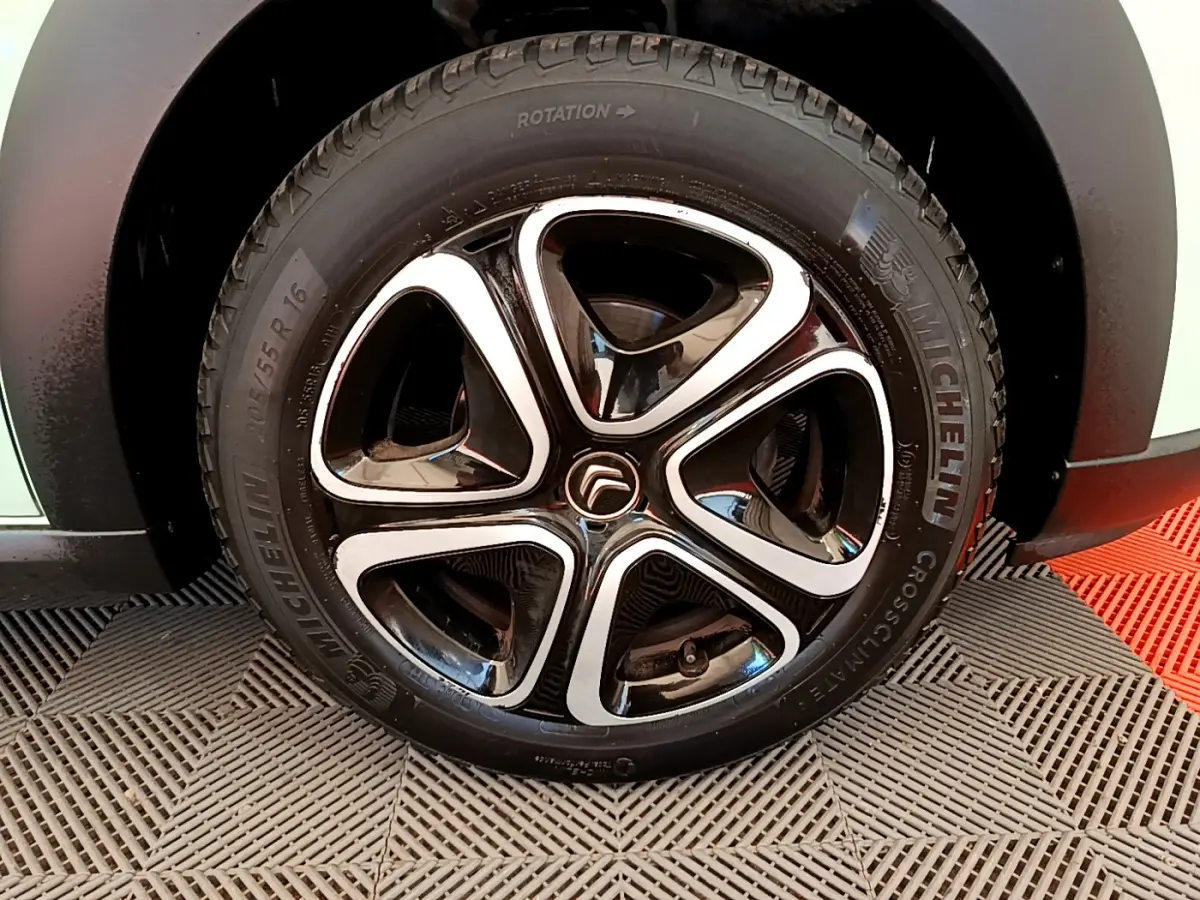 Gros plan sur la jante noire et argentée d'une Citroën C3 PureTech 82 verte, avec pneu Michelin visible.