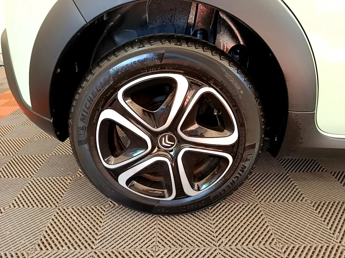 Gros plan sur la roue avant gauche d'une Citroën C3 vert clair, mettant en valeur la jante noire et argentée au design moderne.