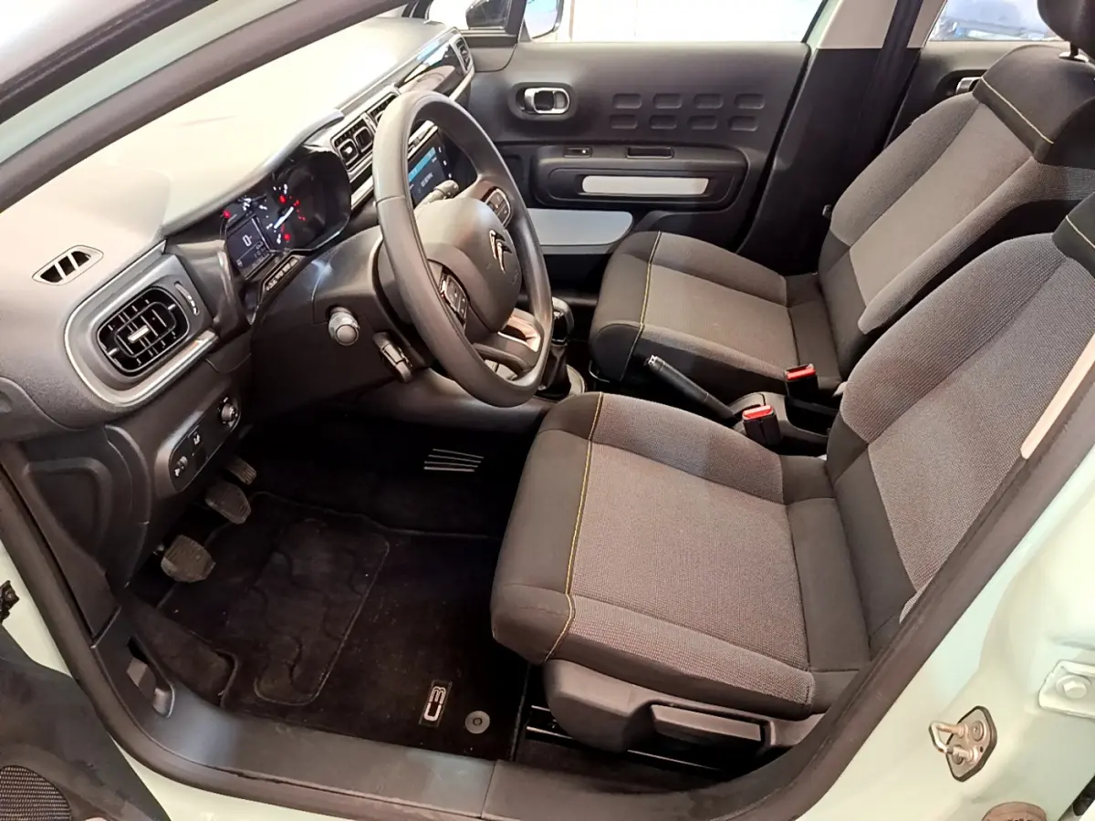 Intérieur avant droit de la Citroën C3 PureTech 82 vert 2019, montrant sièges tissu gris et tableau de bord moderne.