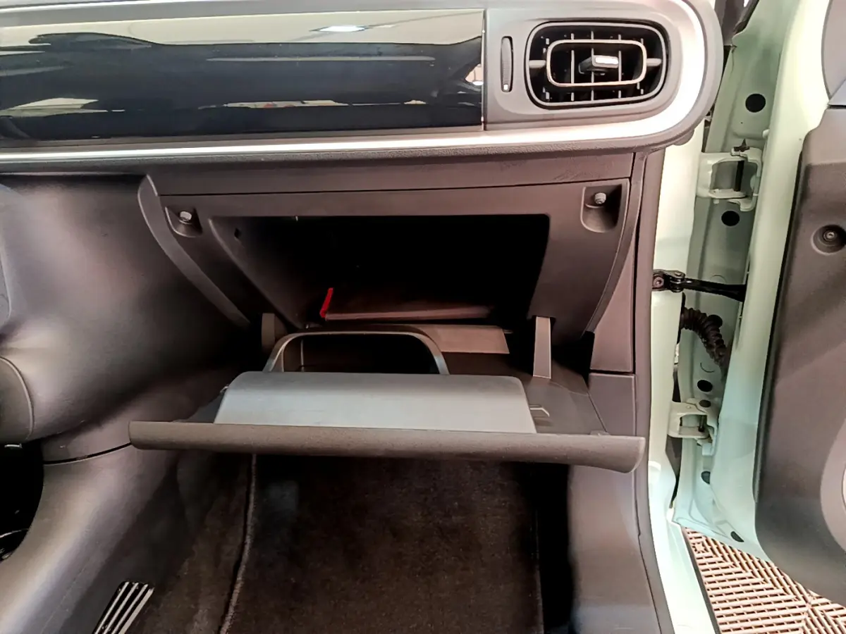 Vue intérieure côté passager du coffre à gants ouvert d'une Citroën C3 2019 vert clair avec tableau de bord noir brillant.