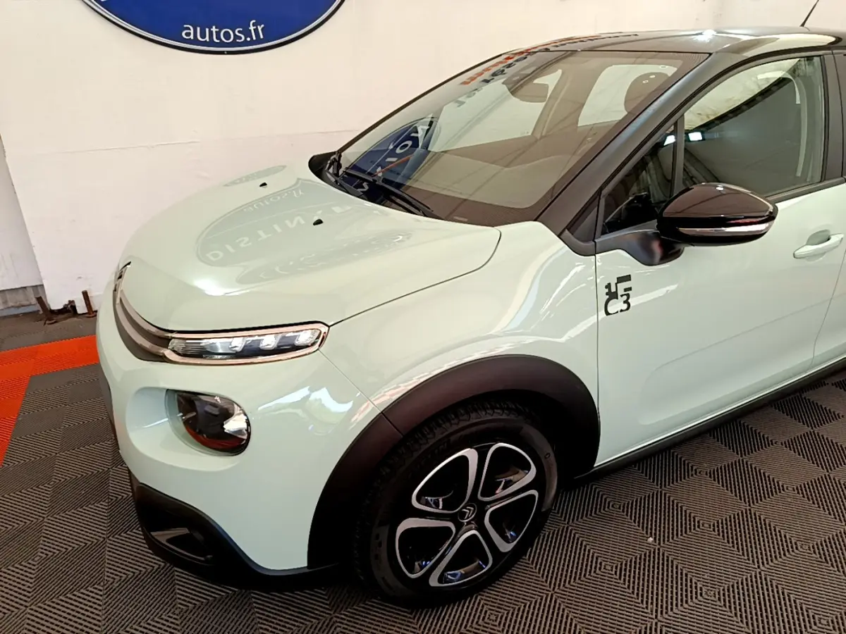 Vue 3/4 avant gauche d'une Citroën C3 PureTech 82 vert clair avec jantes noires et logo C3 sur l'aile.