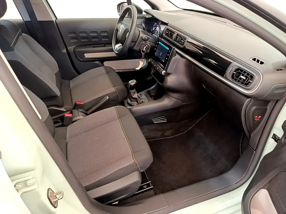 Intérieur avant droit d'une Citroën C3 vert clair 2019 avec tableau de bord noir et écran tactile central.