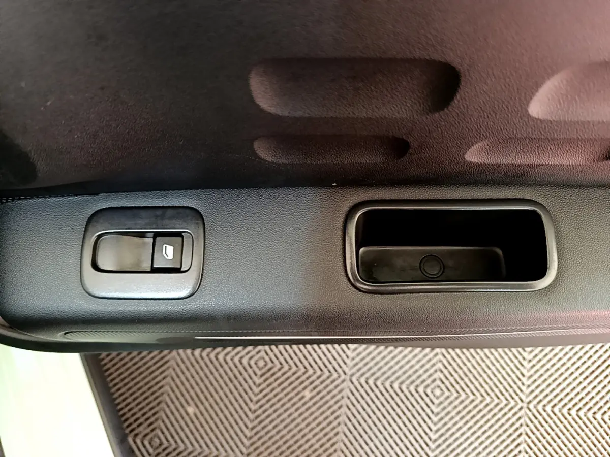 Gros plan sur la poignée intérieure et le bouton de verrouillage de la porte côté gauche d'une Citroën C3 vert 2019.