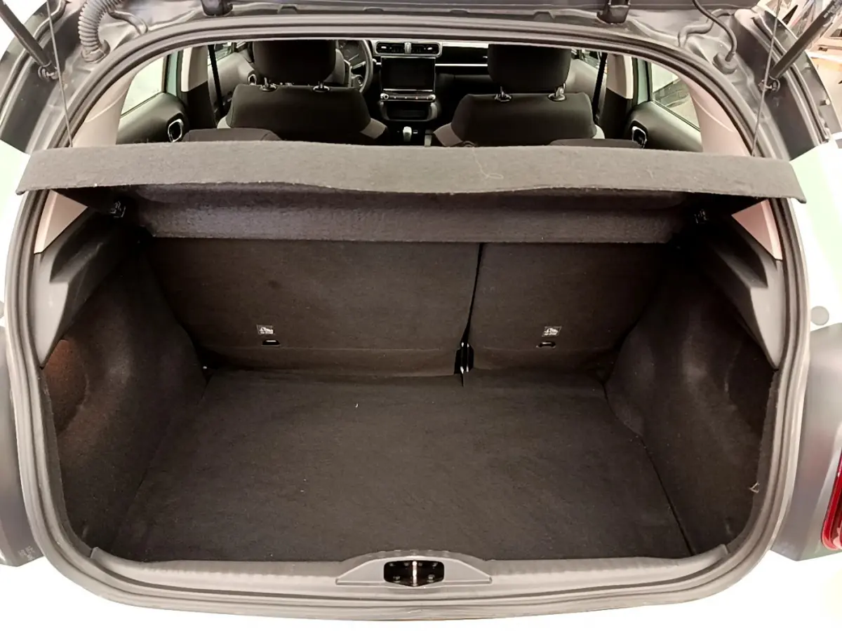 Coffre ouvert vu de l'arrière d'une Citroën C3 vert 2019 avec tablette cache-bagages et sièges arrière noirs.