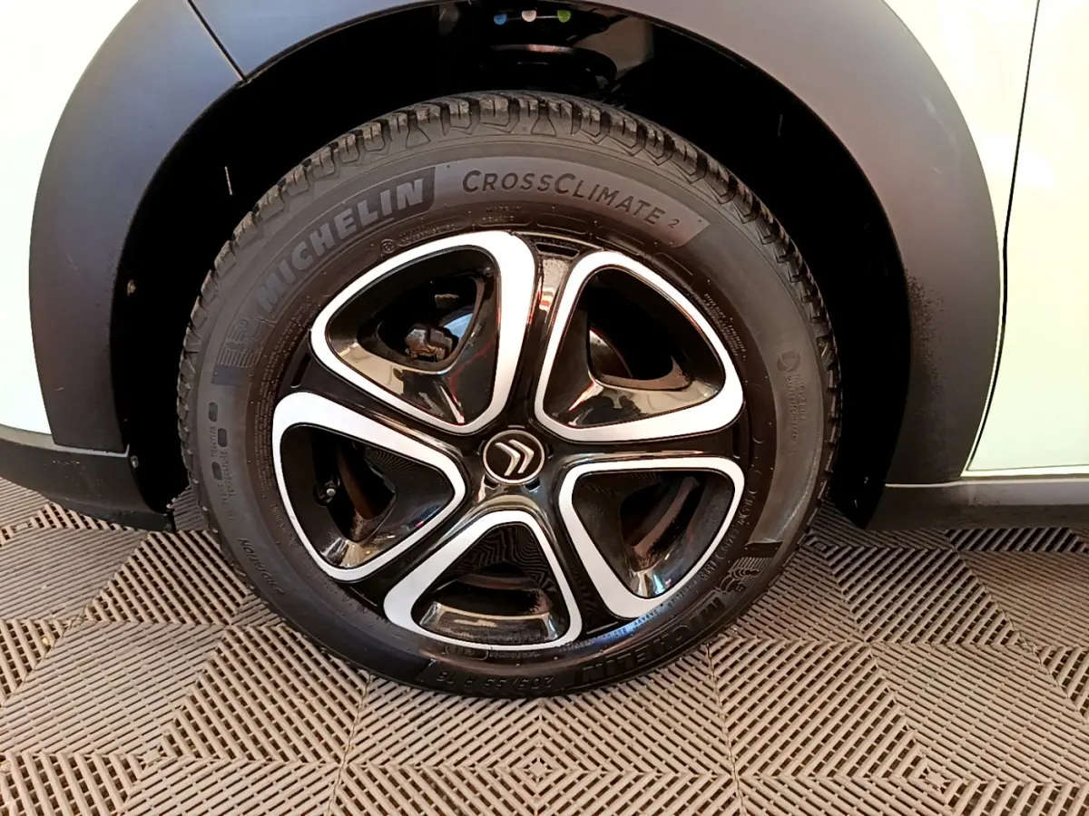 Gros plan sur la roue avant droite d'une Citroën C3 verte avec jante noire et argentée au design moderne.