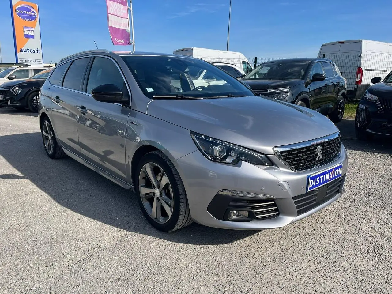 Peugeot 308 SW gris clair vue 3/4 avant droit avec jantes alliage et calandre noire au soleil