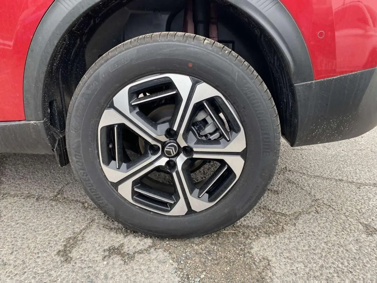 Gros plan sur la roue avant gauche avec jante alliage diamantée du Citroën C3 Aircross Rouge Elixir au toit noir.