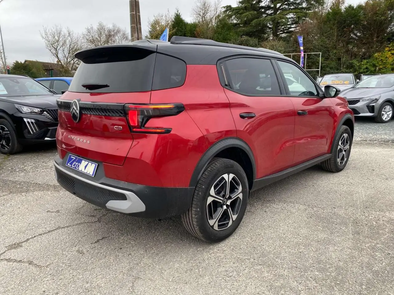 Vue 3/4 arrière droite d'un Citroën C3 Aircross rouge Elixir avec toit noir et jantes alliage 17 pouces.