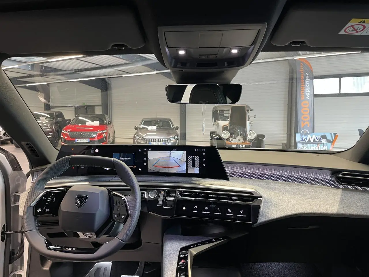 Vue intérieure avant du Peugeot 3008 GT 2025, tableau de bord avec écran panoramique et volant compact noir.