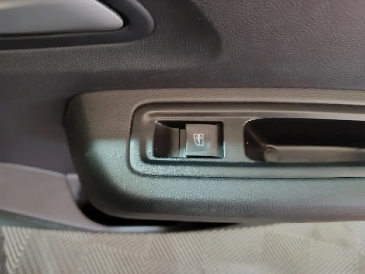 Gros plan sur le bouton de lève-vitre côté conducteur intérieur de la Dacia Sandero Extreme+ TCe 110 verte 2024.