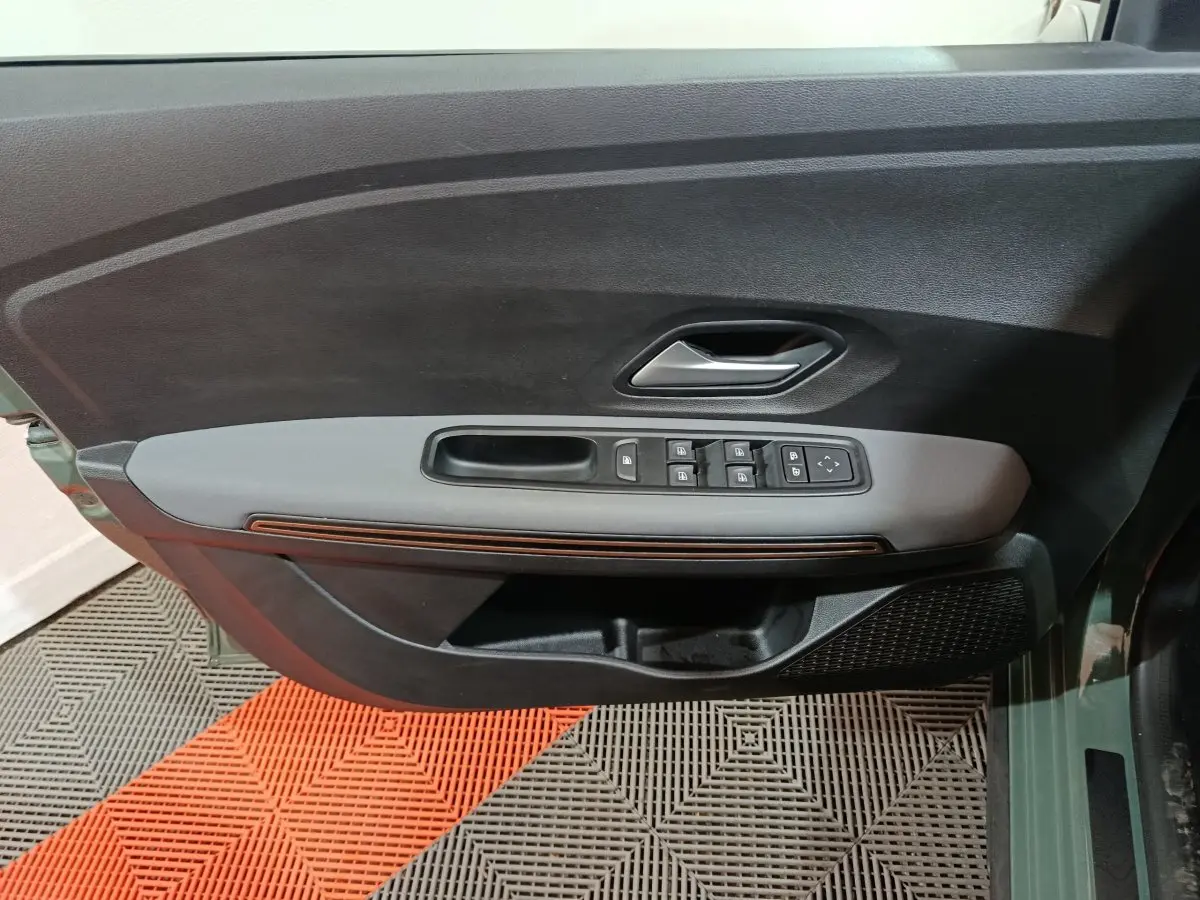 Vue rapprochée de la porte avant gauche de la Dacia Sandero Extreme+ 2024, avec commandes électriques et garniture grise.