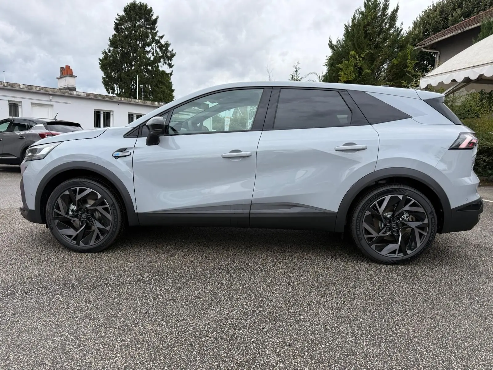 Vue de profil côté gauche du Renault Symbioz gris rafale, soulignant ses jantes noires au design moderne.