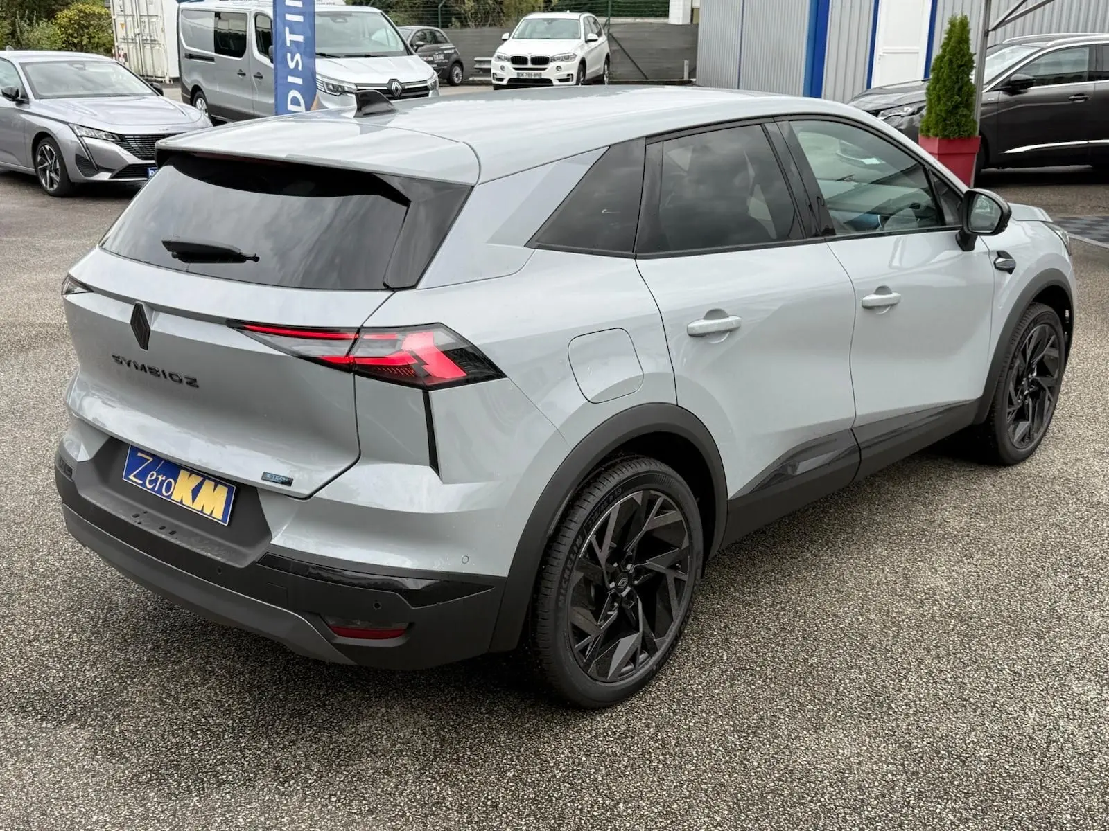 Vue 3/4 arrière droite d'un Renault Symbioz gris Rafale avec jantes noires et feux arrière LED distinctifs.