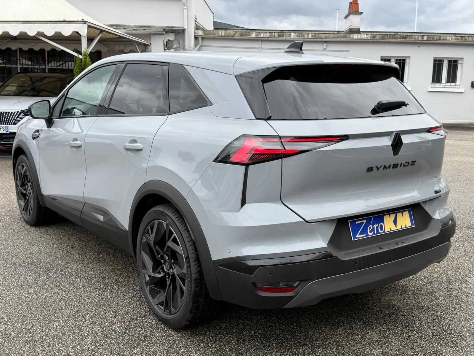 Vue 3/4 arrière droite du Renault Symbioz gris Rafale avec feux arrière LED et jantes noires distinctives.