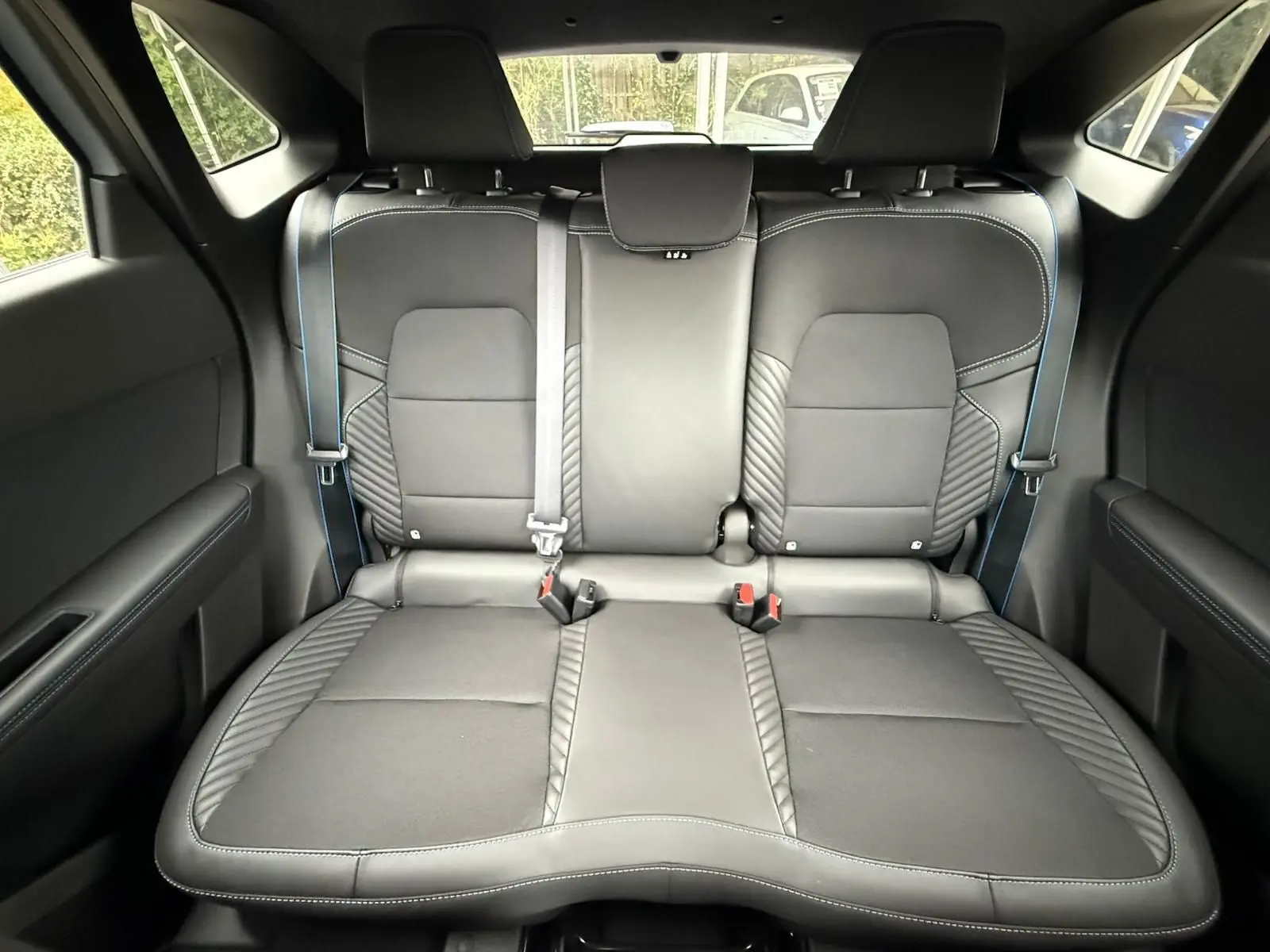 Vue intérieure arrière des sièges noirs en cuir avec surpiqûres bleues du Renault Symbioz gris Rafale 2026.