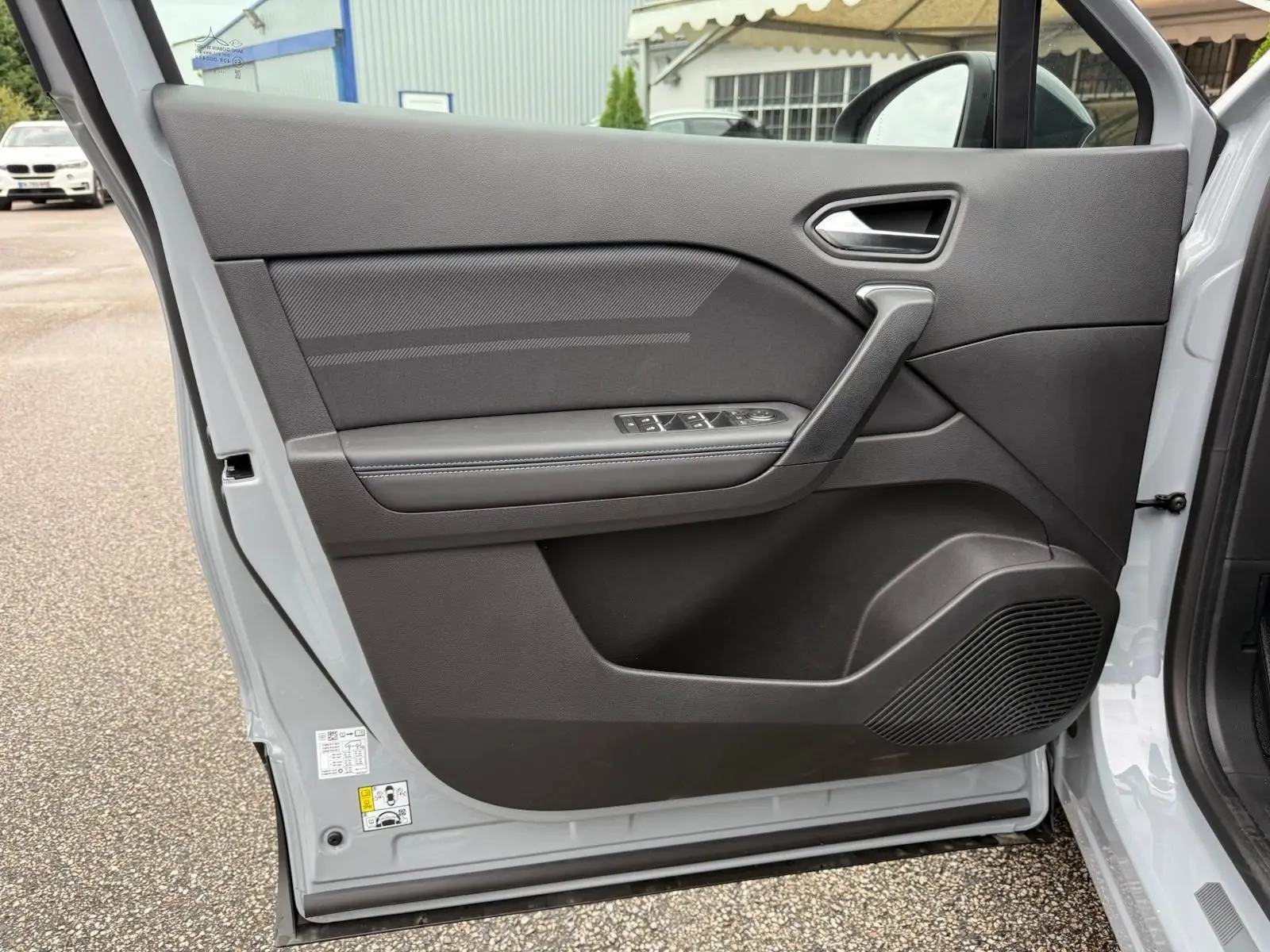 Vue intérieure de la porte avant gauche gris rafale du Renault Symbioz 2026 avec commandes de vitres et haut-parleur intégré.