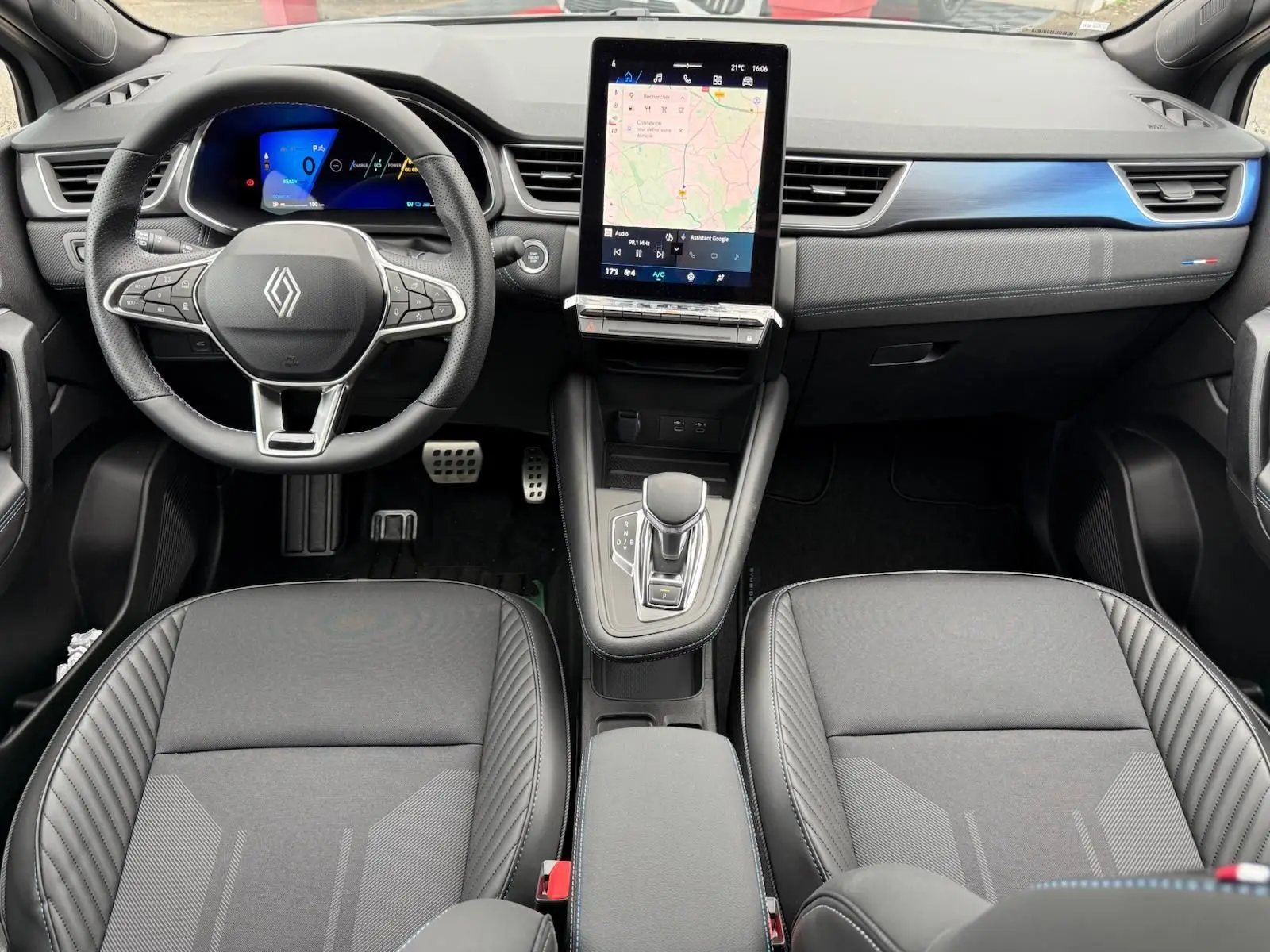 Vue intérieure avant du Renault Symbioz 2026 gris Rafale, avec tableau de bord numérique et écran tactile central vertical.