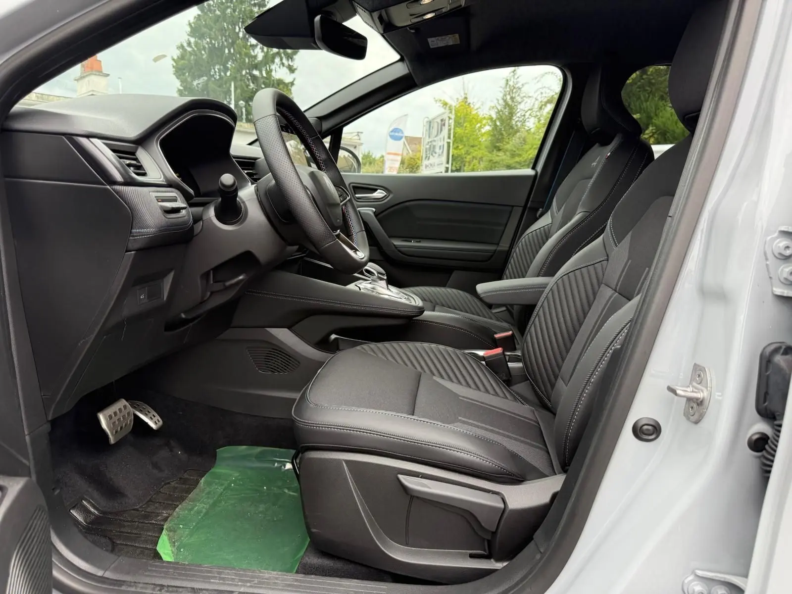 Vue intérieure côté conducteur de la Renault Symbioz 2026, sièges noirs avec surpiqûres et volant multifonction.