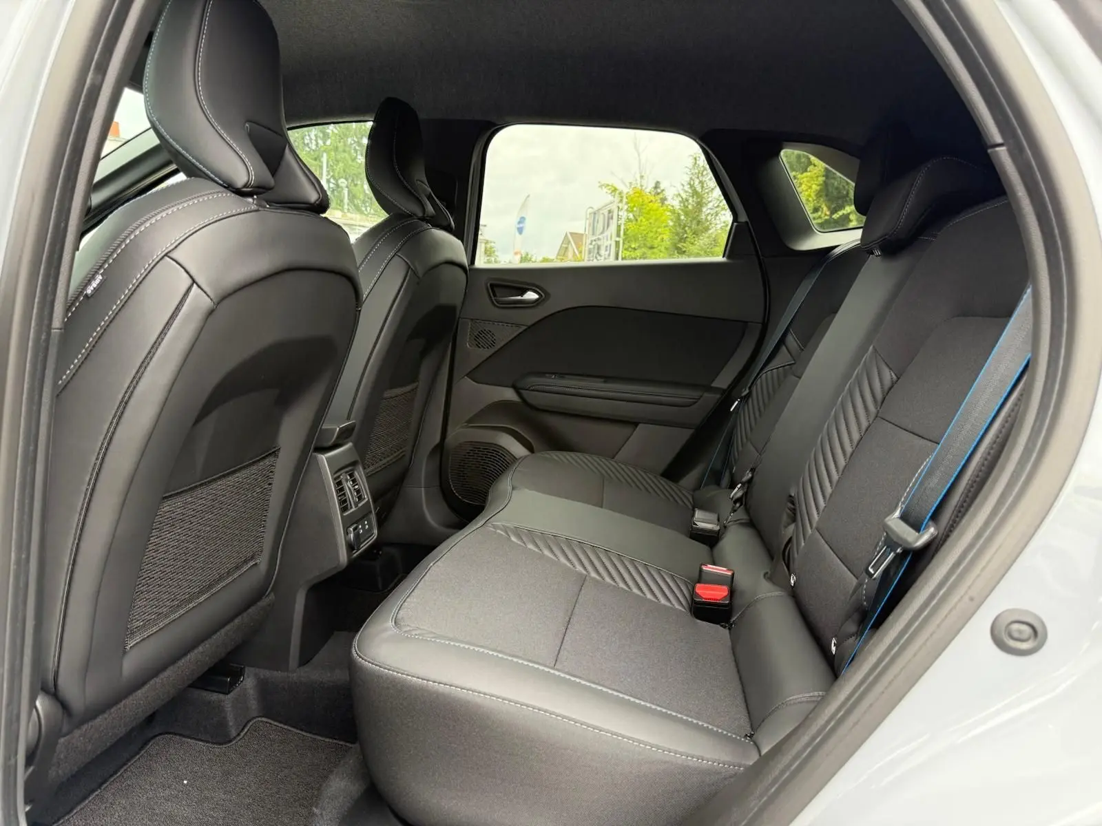 Vue intérieure côté droit des sièges arrière en tissu gris avec surpiqûres bleues du Renault Symbioz 2026.